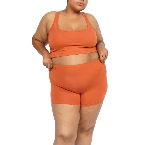 Plus-size model wearing orange shorts and tank top set.