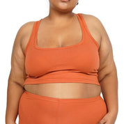 Plus size model wearing rust crop racer tank top.