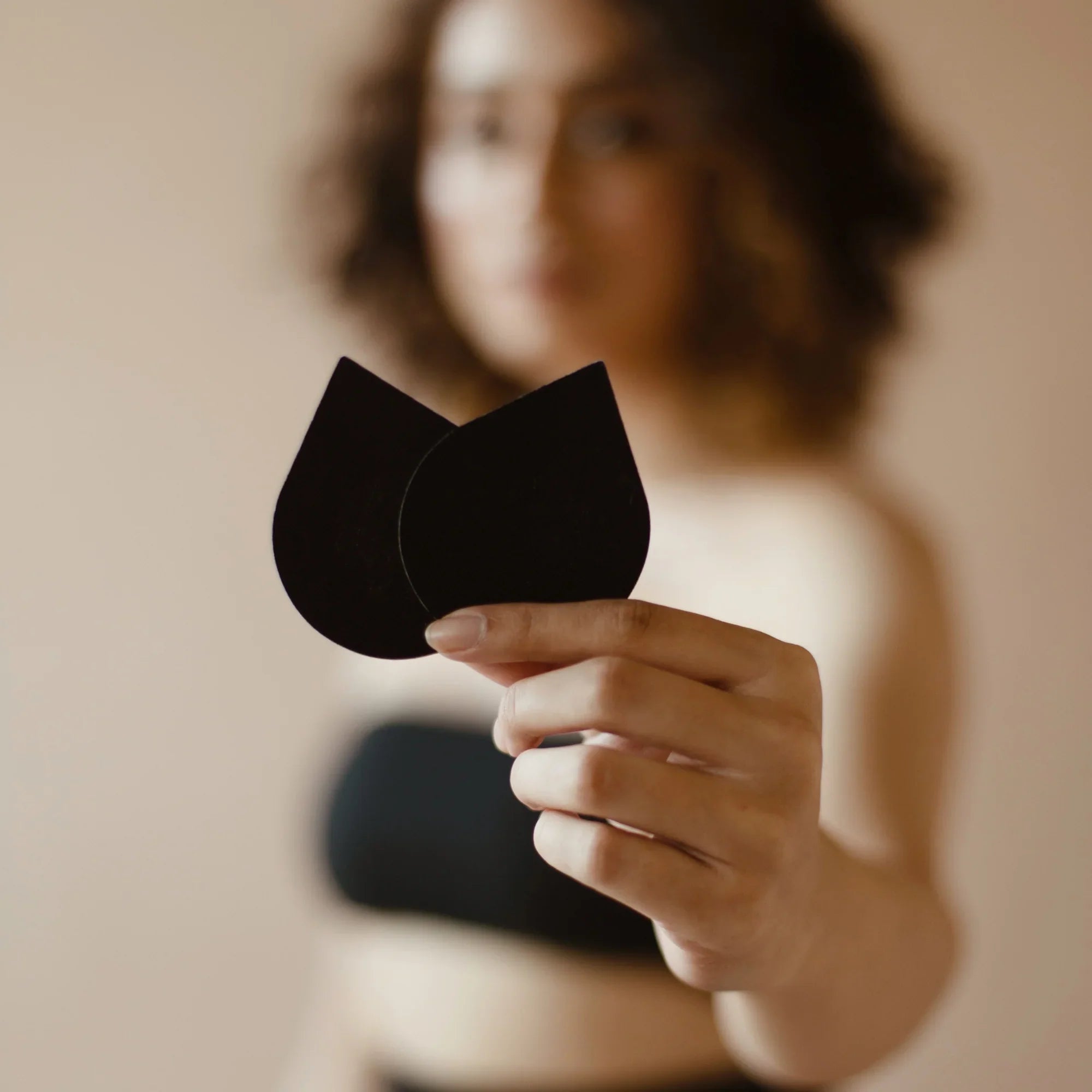 Black pasties held by a model, 50 pairs product.